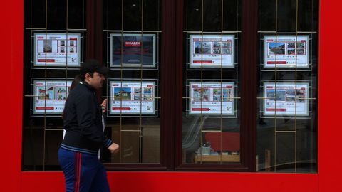 Un viandantes camina por delante de la vitrina de una agencia inmobiliaria en Barbanza.