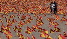 Dos personas pasean por la Playa de la Patacona de Alboraya en la que se han colocado un total de 53.000 banderas de Espa�a en homenaje a los espa�oles fallecidos por coronavirus, en Alboraya, Valencia (Espa�a) a 4 de octubre de 2020. La iniciativa, impulsada por la Asociaci�n Nacional de V�ctimas y Afectados por Coronavirus (ANVAC), colocaron esta madrugada las banderas en la playa de la Patacona de Alboraia (Valencia)