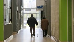 Una pareja de personas mayores pasean por las galer�as comerciales vac�as de un edificio de la avenida da Coru�a