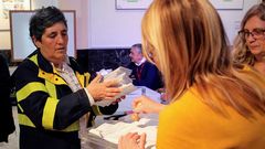 Una trabajadora de Correos entrega a la presidenta de una mesa electoral votos emitidos por correo