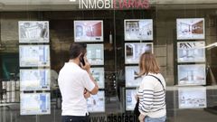 piso.Dos personas consultan los precios de los pisos delante de una inmobiliaria