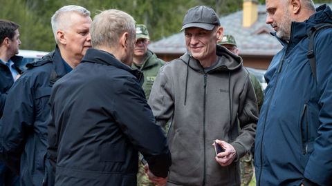El primer ministro polaco, Donald Tusk, estrecha la mano del periodista Andrzej Poczobut tras atravesar la frontera con Bielorrusia