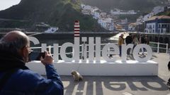Un turista hace una foto a su perro con Cudillero al fondo