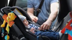 Una padre asegura a su hijo en la silla del coche