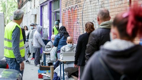 Vecinos realizan una cola para recoger bolsas de la Asociaci�n de Vecinos Parque Aluche (Madrid) donde los voluntarios han entregado alimentos y productos donados en su sede ubicada en la calle Quero n� 69 a aquellas personas que lo necesitan