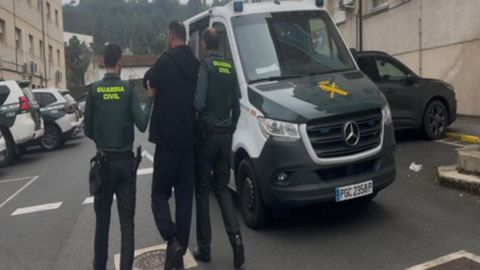 Uno de los detenidos, custodiado por dos agentes de la Guardia Civil