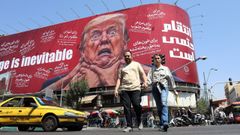 Una pareja pasea por Teher�n junto a una valla publicitaria en contra de Donald Trump.