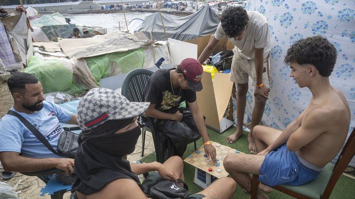Inmigrantes jugando a las damas en una playa de Ceuta.