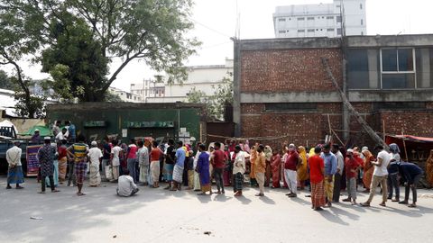 La gente de Bangladesh hace cola, algunos con mscaras protectoras, para comprar alimentos esenciales en una calle de Dhaka, Bangladesh