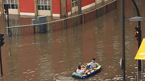 Dos j�venes en una lancha neum�tica, navegan en una inundada calle Llano Ponte, en Avil�s
