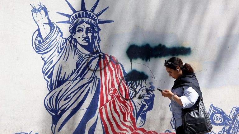 Una mujer pasea por Teher�n (Ir�n) frente a un mural cercano a la embajada de Estados Unidos.