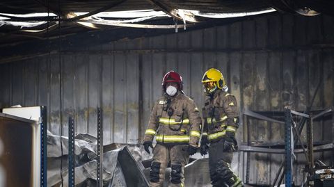 Efectivos antiincendios actuando en el fuego que calcinó parte del interior de una nave industrial en Portas.