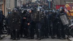 Agentes antidisturbios se parapetan en una calle durante los disturbios del jueves.