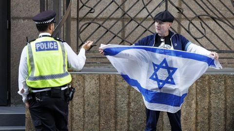 Un agente habla con un contramanifestante que portaba una bandera israel durante una manifestacin contra la extrema derecha frente al Hotel Britannia en Londresenagosto.