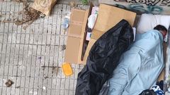 Un sintecho duerme en una plaza de la calle Ram�n Aller