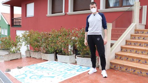 Alberto Rama posa en la puerta de su casa de Esteiro delante del cartel de recibimiento que le hicieron sus vecinos
