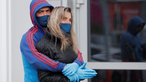 Una pareja se abraza en Kaliningrado, en Rusia, mientras espera delante de uno de los comercios que ya reabrieron
