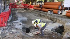 Especialistas en arqueolog�a examinando ayer los restos, con las obras en marcha al fondo.