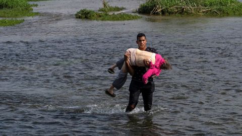 Un migrante venezolano cruza el r�o Grande con una mujer de avanzada edad en brazos