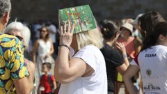 Una mujer aprovecha una revista para taparse del sol en la Praza do Obradoiro