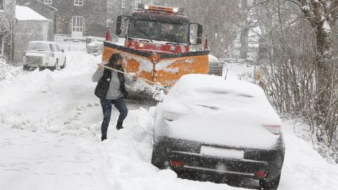 Vecinos de Hospital do Cebreiro intentan retirar un coche cubierto por la nieve para que pueda pasar la quitanieves