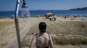 Una mujer en una ducha de la playa de Coroso, en Ribeira