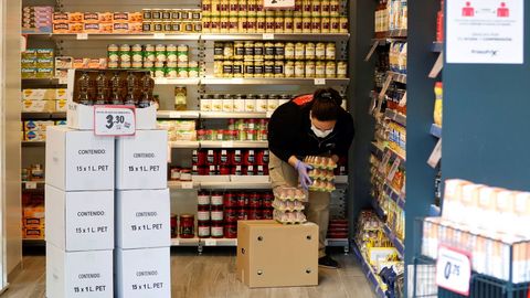 Una mujer carga alimentos en un local comercial, en el centro de Oviedo.