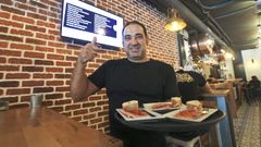 El encargado del Donegal's lleva tres tapas de lac�n, al tiempo que se�ala la pantalla en la que aparecen todos los pinchos salados gratis que ofrece el local