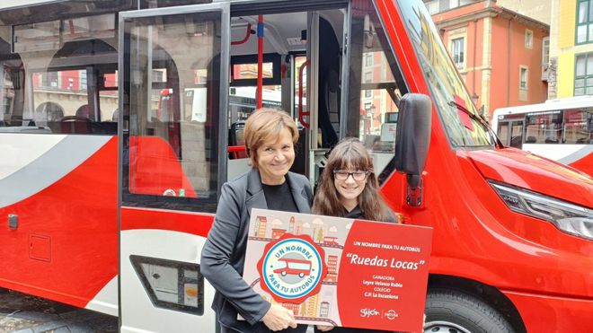 La alcaldesa gijonesa, Carmen Moriy�n, desvela, junto a una alumna del colegio p�blico Escuelona, el nombre de uno de los tres microbuses de la nueva l�nea en zona rural de Emtusa
