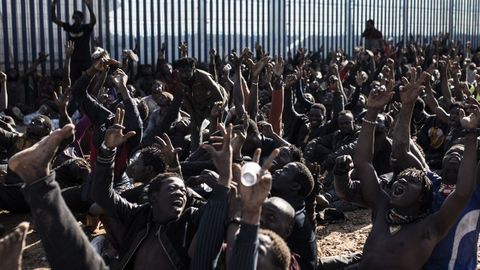 Un grupo de inmigrantes hacen el signo de la victoria tras saltar la valla de Melilla