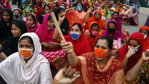 Trabajadoras de la confeccin de Bangladesh, algunas con mscaras protectoras, gritan consignas y bloquean una carretera durante una protesta para exigir el pago de salarios en Dhaka. Miles de trabajadoras del sector no fueron pagadas por las fbricas despus de que se cancelaran exportaciones por valor de alrededor de tres mil millones de dlares debido a la pandemia causada por el coronavirus
