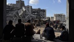 Un grupo de gazates observa los trabajos de rescate de un padre y sus tres hijas, de entre los escombros tras un ataque areo israel contra el edificio donde se refugiaban.