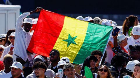 Unas personas sujetan una bandera de Senegal antes de la llegada del papa al muelle.