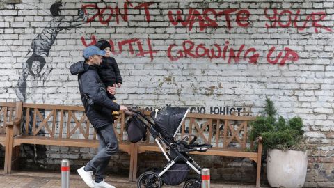 Un mozo ucraíno camiña diante dunha pintada: «Non estragues a túa mocidade medrando».