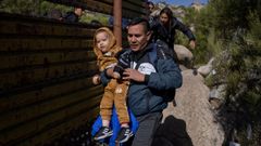 El colombiano Juan Carlos pasa con su hijo de dos a�os, Juan Jos�, y su mujer Anna por una brecha en el muro fronterizo en Boulevard, California.