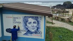 El autor, Manuel Carballeira, ultimando la pintura del mural, en la playa peque�a de A Frouxeira