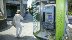 Una mujer pasa al lado de una cabina mientras habla por el m�vil, la principal causa de su abandono