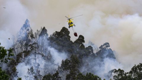 Un helic�ptero trabaja en el incendio forestal en la localidad asturiana de Pe�aflor (Grado)