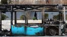 Una mujer iran� vestida con el chador negro pasa ante un bus calcinado en unas protestas que cesaron hace d�as
