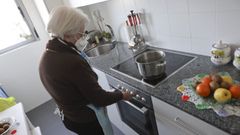 En la imagen, una vecina del edificio calienta agua en la cocina para el aseo diario