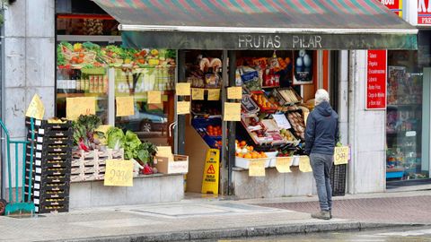 Un cliente espera en el exterior de una fruter�a, en Oviedo