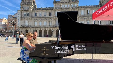 Una pareja toca uno de los pianos situados en la plaza de Mar�a Pita dentro de la iniciativa �Tu ciudad se llena de pianos�