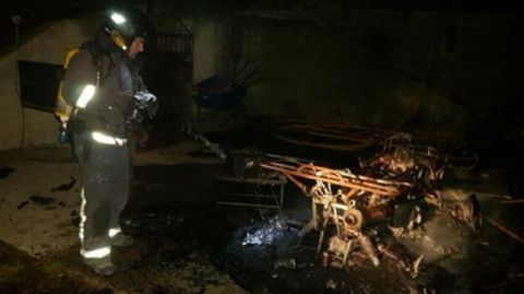 Un bombero ante uno de los enseres afectados por el incendio en El Castrill�n (Laviana)