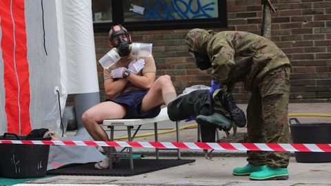 Un soldado con traje de protecci�n ayuda a su compa�ero a retirarse el suyo adecuadamente