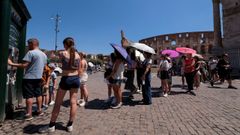 Un grupo de turistas se protegen del sol con paraguas junto al Coliseo de Roma
