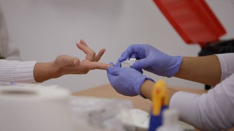Personal sanitario de Cruz Roja saca sangre de un dedo a una persona para realizar el test rápido de detección de anticuerpos IgG e IgM en Madrid