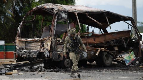 Un militar camina junto a los restos de un autobús calcinado a causa de una bomba en Villa Rica (Colombia)