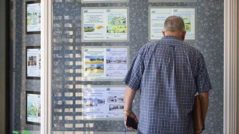 Una persona mira las ofertas de alquiler y venta en el escaparate de la inmobiliaria Javier Tovar