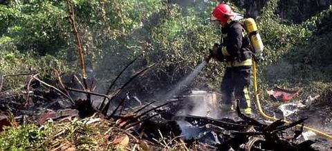 Un bombero sofoca el fuego junto a una chabola en el casco. 