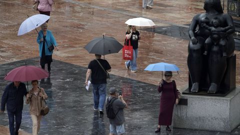 Viandantes con paraguas bajo la lluvia en la plaza de La Escandalera